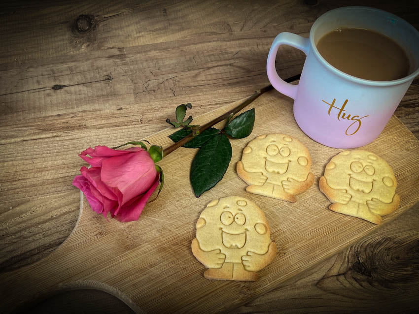 three cookies on a wood chopping board with a pink rose
